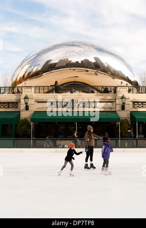 People ice skate at the McCormick Tribute Plaza and Ice Rink with the Cloud Gate sculpture behind. Stock Photo