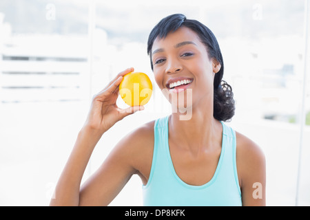Delighted black haired woman holding an orange Stock Photo