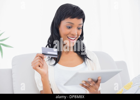 Amazed black haired woman buying online with her tablet pc Stock Photo