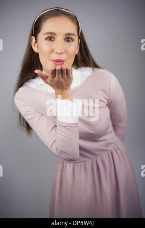 Happy young model with pink dress on sending an air kiss to camera Stock Photo