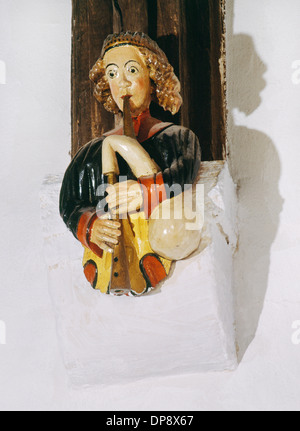 Wooden figure (C15th) on roof beam support on N wall of chancel of Llaneilian Church, Anglesey: angel/musician playing a bagpipe Stock Photo