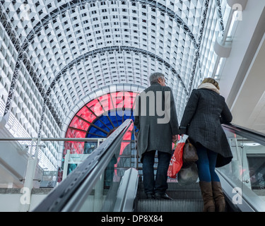 Man and woman shoppers on escalator under domed roof of the Bentall Centre, shopping mall - Kingston upon Thames, Greater London Stock Photo