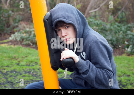 A teenage boy sitting on a swing looking depressed. Stock Photo