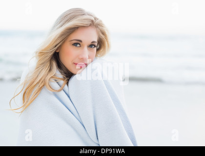 Calm blonde woman warming herself in a blanket Stock Photo