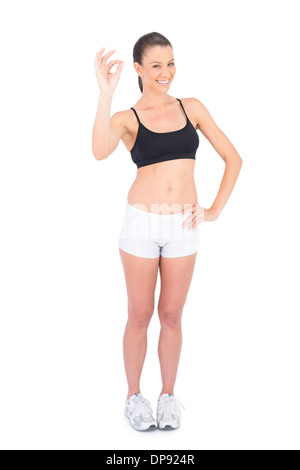 Portrait of happy woman in sportswear making okay gesture Stock Photo