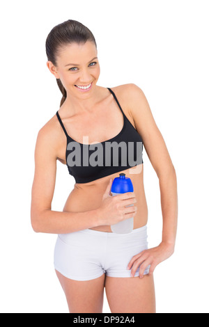 Smiling toned woman in sportswear holding flask Stock Photo