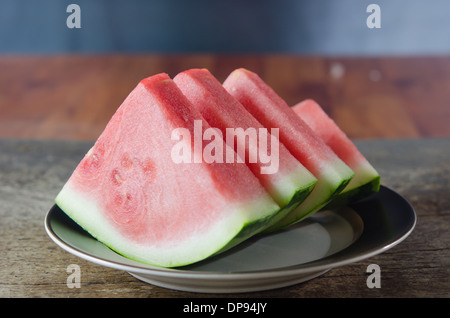 Slices of watermelon on dish over wooden board Stock Photo