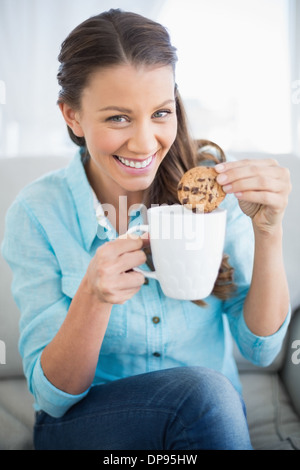 Smiling woman dunking cookie in coffee Stock Photo