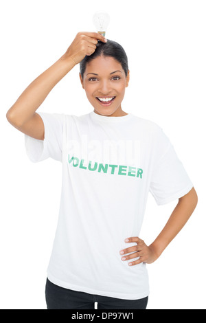 Smiling model wearing volunteer tshirt holding light bulb above her head Stock Photo