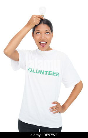 Happy model wearing volunteer tshirt holding light bulb above her head Stock Photo