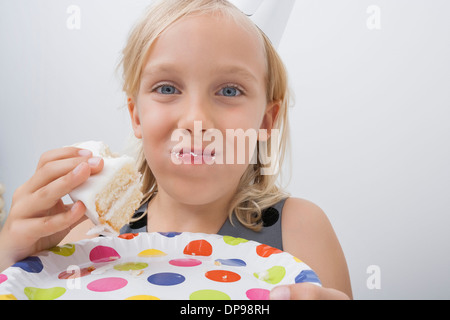 Close-up of cute girl eating birthday cake against gray background Stock Photo