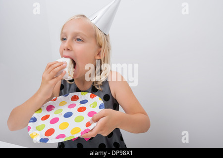 Cute girl eating birthday cake slice at home Stock Photo