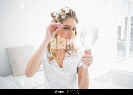 Peaceful natural blonde using tweezers on her eyebrow Stock Photo