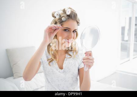 Smiling natural blonde using tweezers on her eyebrow Stock Photo