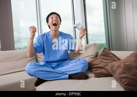 Full length of excited mid adult man playing video game in living room Stock Photo