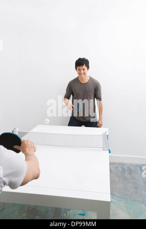 Happy Asian man playing ping pong with friend Stock Photo