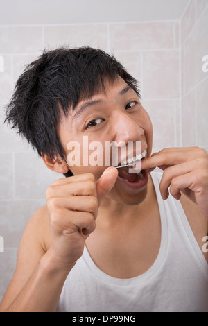 Portrait of mid adult man flossing his teeth in bathroom Stock Photo