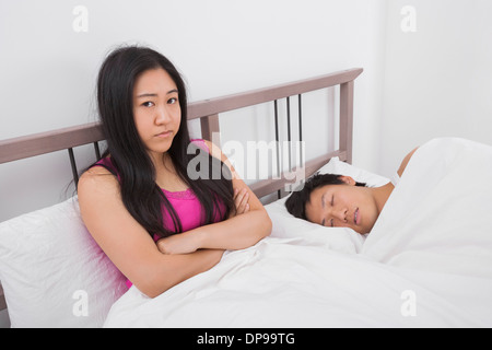 Portrait of displeased woman with man sleeping in bed Stock Photo