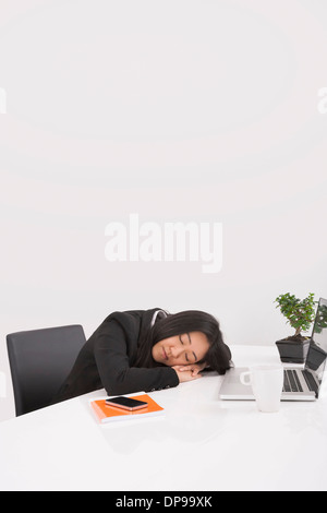 Tired businesswoman resting at desk in office Stock Photo