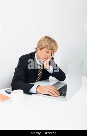 Stressed businessman using laptop at desk in office Stock Photo