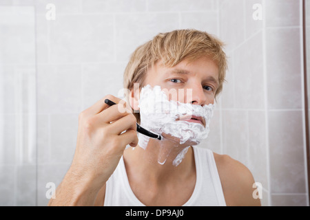 Portrait of mid-adult man shaving in bathroom Stock Photo