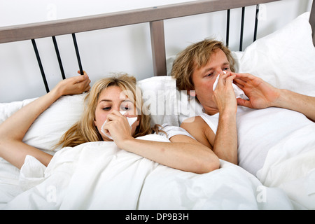 Couple suffering from cold lying on bed Stock Photo