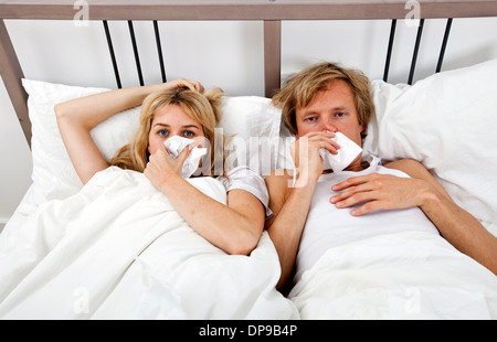 Portrait of couple suffering from cold lying on bed Stock Photo
