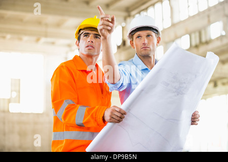 Male architects with blueprint working at construction site Stock Photo