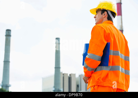 Back view of male architect with clipboard standing at site Stock Photo