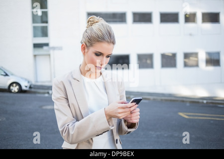Thoughtful stylish businesswoman sending a text Stock Photo