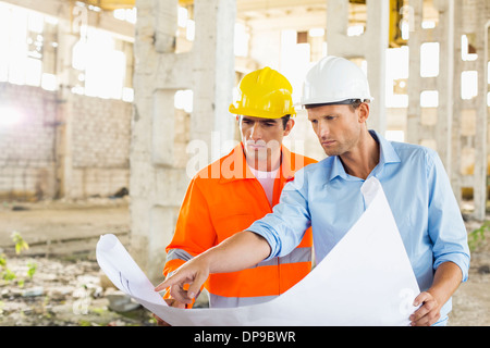 Male architects discussing over blueprint at construction site Stock Photo