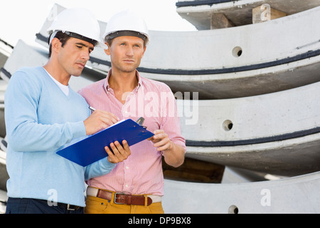 Architects with clipboard working at construction site Stock Photo