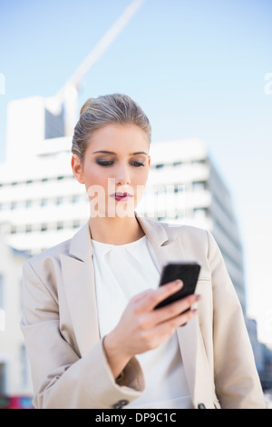 Serious attractive businesswoman sending a text message Stock Photo