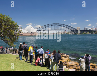 Tourists view Sydney Harbour Bridge and Opera House from Royal Botanic Gardens, Sydney, Australia Stock Photo
