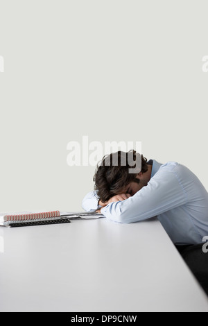 Young businessman resting head on desk Stock Photo