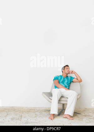 Full length of thoughtful young man sitting on chair Stock Photo