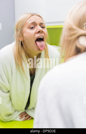 Young woman examining tongue in mirror Stock Photo