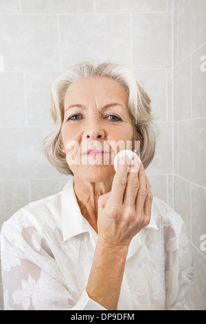 Portrait of senior woman applying face powder in bathroom Stock Photo