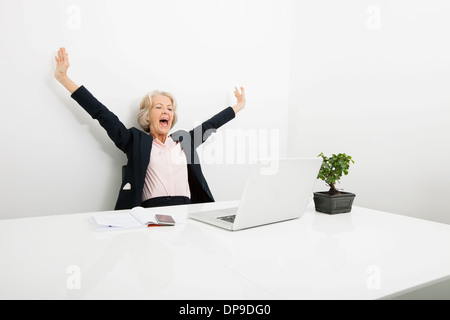 Senior businesswoman yawning while looking at laptop in office Stock Photo