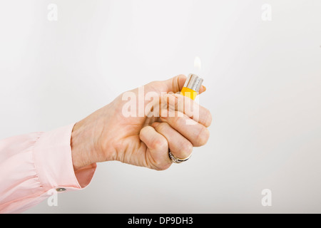 Businesswoman's hand holding cigarette lighter with flame in office Stock Photo