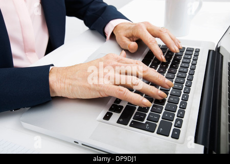 Cropped image of senior businesswoman typing on laptop Stock Photo