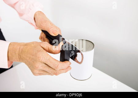 Cropped image of senior businesswoman opening canned food at office Stock Photo