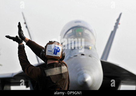 U.S. Navy Airman signals to the pilot of an F/A-18F Super Hornet aircraft