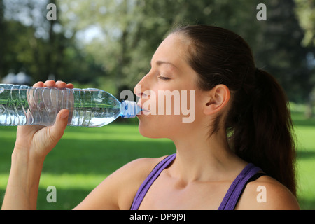 Sporty woman drinking water from a bottle after jogging or running Stock Photo