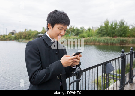 Happy mid adult businessman text messaging through mobile phone at bridge railing Stock Photo
