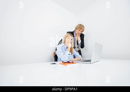 Businesspeople with hand on chin looking at laptop in office Stock Photo
