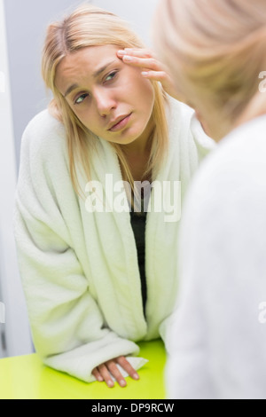 Young woman examining eye in mirror Stock Photo