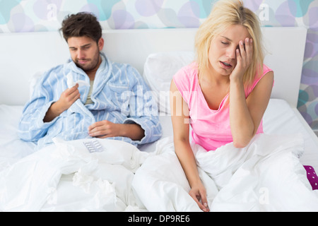 Irritated sick couple on bed at home Stock Photo
