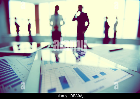 Close-up of business document in touchpad at workplace on background of office workers interacting Stock Photo