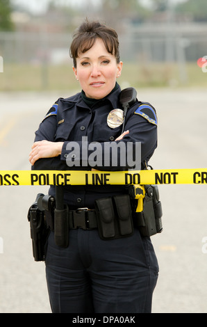 A Hispanic female police officer standing at a crime scene. Stock Photo